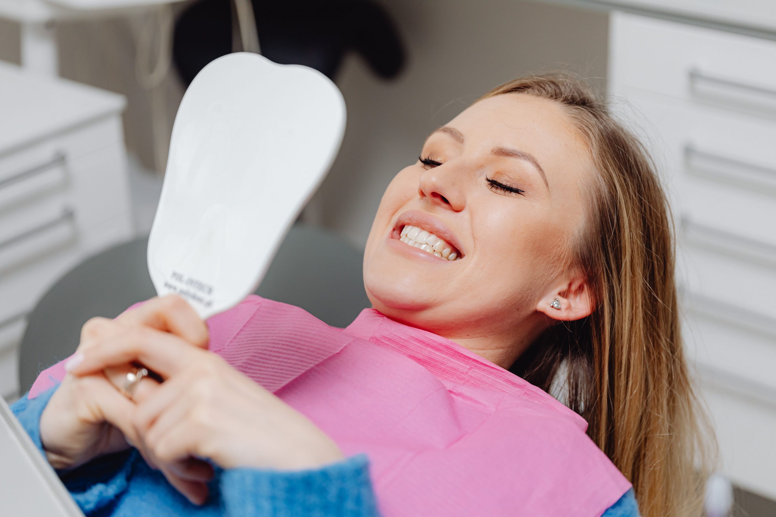 A happy patient admiring her smile at A Helena Jimenez DDS